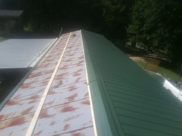Old rusted panels beside newly installed green metal roofing — Wind Damage Roof Repair by Roofing Brothers in Ripon