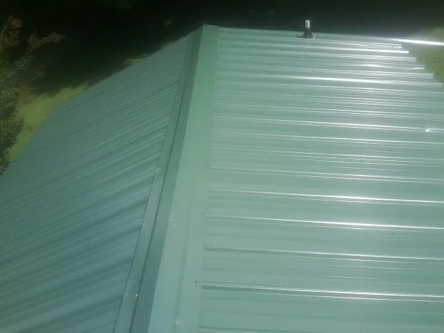 New green metal panels meeting at the ridge of a roof — Flat Roof Repair work by our crew in Ripon