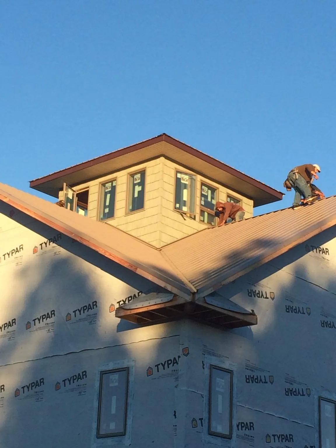 Roofers working around a rooftop cupola on a new metal roof at sunset — Roof Waterproofing in Ripon by Roofing Brothers